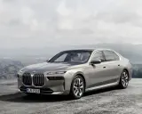 Eleganckie, srebrne BMW 7 2025 z niebieskimi akcentami na felgach, zaparkowane na tle górskiego krajobrazu.