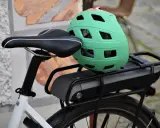Zielony kask na bagażniku roweru elektrycznego, obok siodełka. Baterie do rowerów elektrycznych są gotowe do długiej podróży.
