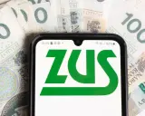 Dodatek pielęgnacyjny z ZUS: sprawdź, komu przysługuje. Na ekranie telefonu logo ZUS, w tle banknoty 100 zł.