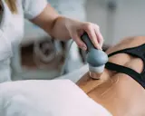 Fizjoterapeuta stosuje głowicę do terapii ultradźwiękami na plecy pacjentki, wspomagając regenerację.