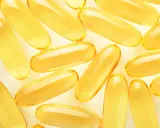 Żółte kapsułki omega 3 ułożone na jasnym tle. Kiedy brać omega 3? Najlepiej po posiłku, by zwiększyć wchłanianie.