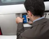 Mężczyzna montuje tablicę rejestracyjną. Kupił auto, ale poprzedni właściciel nie przerejestrował go.