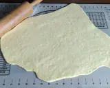 Pâte à beignet légère et croustillante étalée sur un tapis de pâtisserie avec un rouleau à pâtisserie en bois.