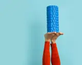 Beine in der Luft, ein blauer Faszienroller balanciert auf den Füßen. Ein Zeichen für das effektive Faszien entgiften und Regeneration.