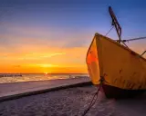 Żółta łódź na plaży w Niechorzu podczas zachodu słońca. Piękne niechorze atrakcje nad morzem.