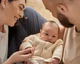Una madre sonríe a su bebé, mientras el padre lo abraza. A pesar de que mi bebé no tiene apego conmigo, la familia se ve unida.