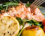 En saftig laxsida i ugn, perfekt kryddad med peppar och örter, serverad med citron, körsbärstomater och färsk spenat.