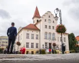 Mężczyzna podziwia ratusz w Trzebnicy, jedną z głównych atrakcji miasta. W tle czerwone serce i kwitnące kwiaty.