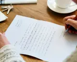 Pisanie listu po angielsku, wzór: "It's been a while since we haven't met...". Na stole klucze, koperty i filiżanka kawy.
