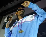 Snoop Dogg w błękitnej bluzie z naszyjnikiem, trzymający mikrofon. Ile pali? Tego nie wiemy, ale na pewno daje czadu na scenie!