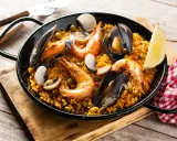 Pyszna paella z owocami morza, idealna do przygotowania z ryżem bomba. Krewetki, małże i cytryna dopełniają danie.