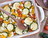 Gebackener Feta mit Zucchini, Kirschtomaten und gelber Paprika in einer Auflaufform, bereit zum Servieren.