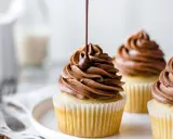 Glaçage onctueux de ganache montée mascarpone sur des cupcakes. Un filet de chocolat coule sur le glaçage.