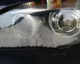 Zaparowany reflektor od środka, z licznymi kropelkami wody na kloszu.