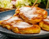 Délicieux Apfelkiechle saupoudrés de sucre glace sur une assiette bleue. Une recette gourmande à essayer !