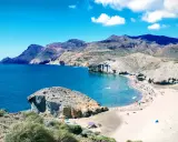 Sonnige playa de mónsul mit türkisfarbenem Wasser, Bergen und vielen Badegästen.