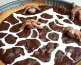 Tarte au chocolat d'Halloween décorée d'une toile d'araignée en glaçage blanc et d'araignées en pâte d'amande.