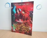 Okładka książki "Heaven Official's Blessing" z dwoma mężczyznami pod czerwonym parasolem.