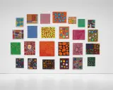 A vibrant collection of paintings by top visual artists, featuring bold colors and abstract patterns, adorns a white gallery wall.