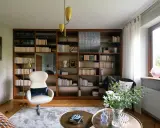 Duży regał na książki za kanapą, wypełniony po brzegi tomami, tworzy przytulną atmosferę.