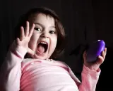 Niño asustado grita con la boca abierta, levantando una mano y sosteniendo un objeto morado.