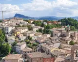 Un borgo pittoresco sulle colline riminesi, con tetti rossi, una chiesa con campanile e un paesaggio verdeggiante sullo sfondo.