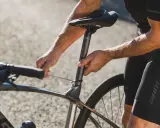 Rowerzysta reguluje wysokość siodełka w rowerze szosowym, używając klucza imbusowego.