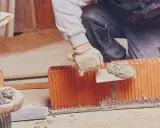 Murarz nakłada zaprawę murarską do bloczków betonowych na budowie.