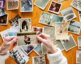 Mani anziane sfogliano vecchie foto stampate su un tavolo di legno, un modo per conservare le foto stampate e i ricordi.