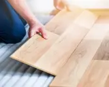 Man colocando una tabla de madera para poner suelo de tarima flotante.