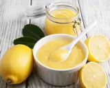 Aksamitny curd cytrynowy w miseczce, obok cytryny i słoiczek z tym pysznym kremem. Idealny do deserów!