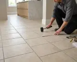 Hombre colocando baldosas en el suelo con un mazo de goma.