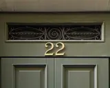 Złote **anielskie liczby** 22 na zielonych drzwiach.