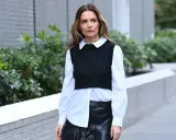 Donna con camicia bianca e gilet nero, la camicia dentro i pantaloni di pelle nera.