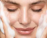 Une femme au visage frais, les yeux fermés, savoure la mousse d'un nettoyant. La définition de la pureté.