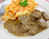 Un plat de rognon de boeuf en sauce, servi avec une purée de pommes de terre et carottes, garni de persil.