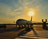 Samolot flydubai na lotnisku o zachodzie słońca. Pracownicy przygotowują bagaż rejestrowany, sprawdzając jego wymiary przed załadunkiem.
