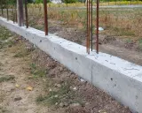 Solidna podmurówka z betonu z wystającymi prętami zbrojeniowymi, gotowa na dalsze prace budowlane.