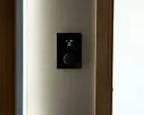 Nowoczesny termostat steruje ogrzewaniem elektrycznym, pokazując temperaturę 27 stopni.
