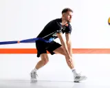 Volleyballspieler im Krafttraining mit Widerstandsband, bereit für den Aufschlag.