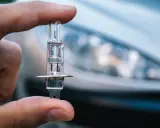 Un dedo sostiene una bombilla de coche, lista para iluminar el camino con sus luces largas.