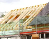 Neuer Dachstuhl im Bau, Gerüst und Schutznetze. Informieren Sie sich über die dachstuhl erneuern kosten.