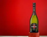 Butelka Martini Brut 7.5% alc. vol. na tle czerwonej ściany.