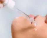 Kropla serum z kwasami AHA spada na skórę.