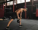 Mężczyzna wykonuje trening funkcjonalny ćwiczenia z kettlebell w siłowni.