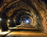 Wąski tunel w kopalni, oświetlony lampami, prowadzi w głąb ziemi. To jedne z wielu tajemniczych jaskiń Dolnego Śląska.