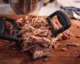 Pulled pork mit Fleischgabel auf Holzbrett. Perfekt für Smoker Rezepte Schwein, z.B. Pulled Pork Sandwiches.