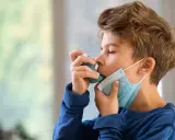 Junge mit Inhalator und Maske. Gute Behandlung beeinflusst die asthma lebenserwartung positiv.