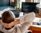Praca po informatyce: programista zrelaksowany przed ekranem z kodem i danymi.