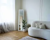 Elegante decoracion salon pequeño con sofá curvo, espejo antiguo y planta.